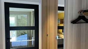 Una habitación moderna con puerta corredera a un balcón, suelo de madera y perchero.