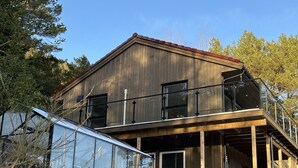 Una casa de madera de dos pisos con un balcón y ventanas grandes.