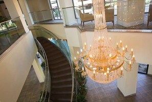Uma escadaria imponente com um candelabro em um amplo saguão.