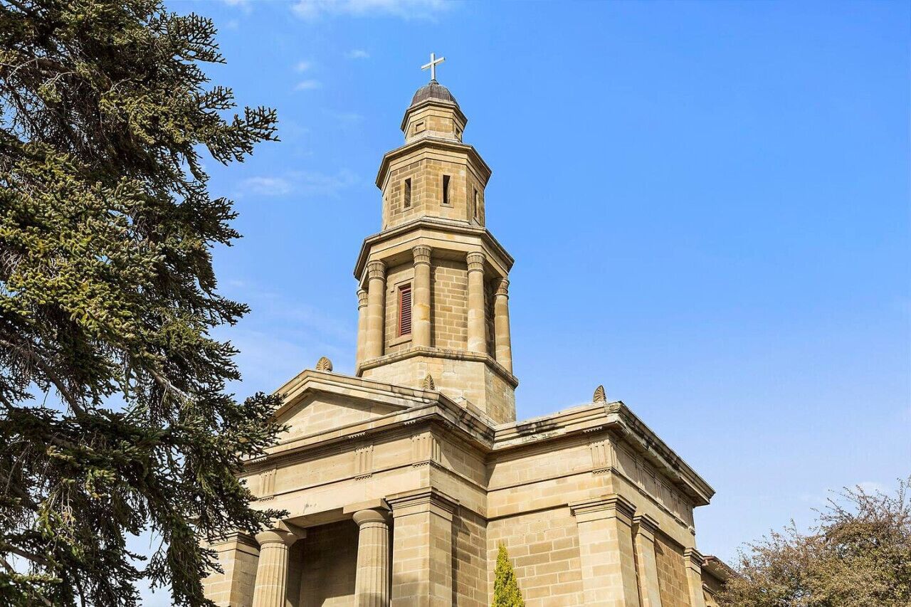 Una iglesia con un campanario destacado y una cruz en la parte superior.