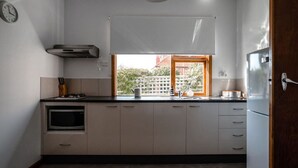 A modern kitchen with white cabinets, a built-in oven, a window with a view, and a ceiling light.