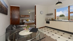 A compact living space with a dining area, kitchenette, and a bedroom.