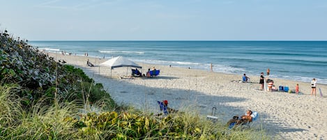 Une plage avec des gens, des tentes et des chaises de plage.