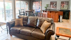 Ein modernes Wohnzimmer mit einer Ledersofa, einem Couchtisch und einem Essbereich mit einer Bar.