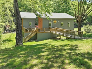 A two-story building with a wooden deck and stairs leading to a door. - Hot Tub+Fire Pit, On the River, WiFi, Grill, Cozy! (Burnsville)