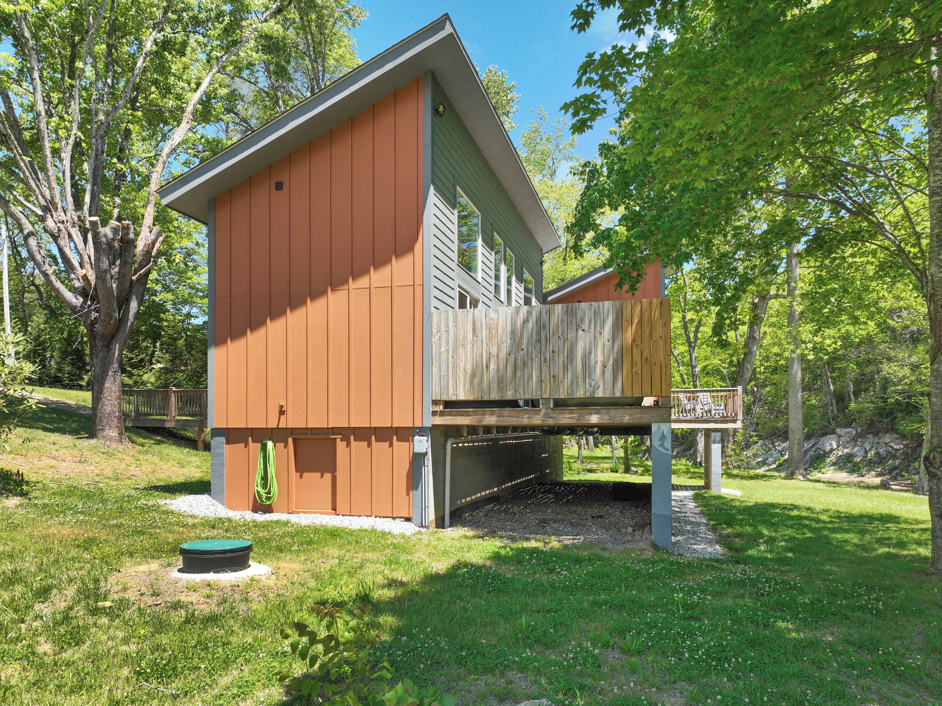 A single-story building with a sloped roof, a wooden deck, and a fenced area.