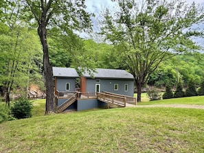 A two-story cabin with a wooden deck and stairs leading to a balcony. - Hot Tub+Fire Pit, On the River, WiFi, Grill, Cozy! (Burnsville)