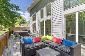 A deck with outdoor furniture, a hot tub, and a covered barbecue area. - Hot Tub+Fire Pit, On the River, WiFi, Grill, Cozy! (Burnsville)
