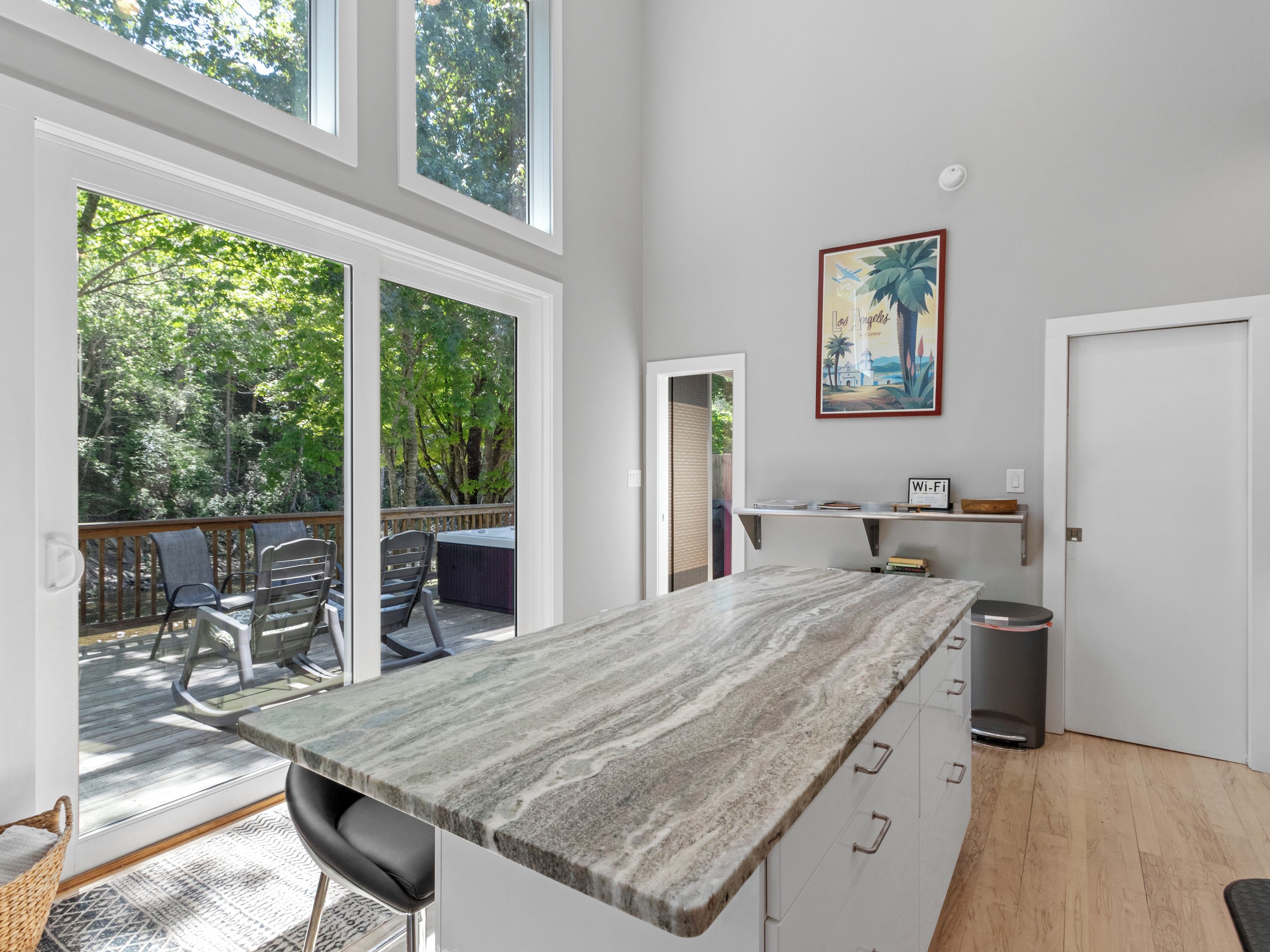 Cozinha moderna com bancada de mármore, banheira de hidromassagem e vista para uma área arborizada.
