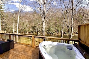 Relax on the deck overlooking the serene river, where you can unwind in the hot tub or enjoy the peaceful surroundings.