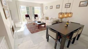 A modern living room with a dining area, featuring a large table, chairs, and a sofa.