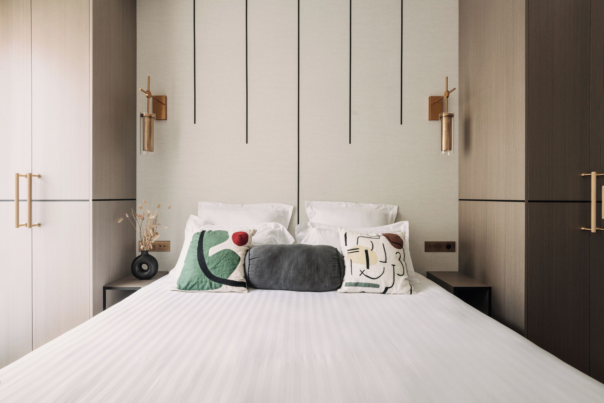 A modern bedroom with a large bed, bedside tables, and a wardrobe.