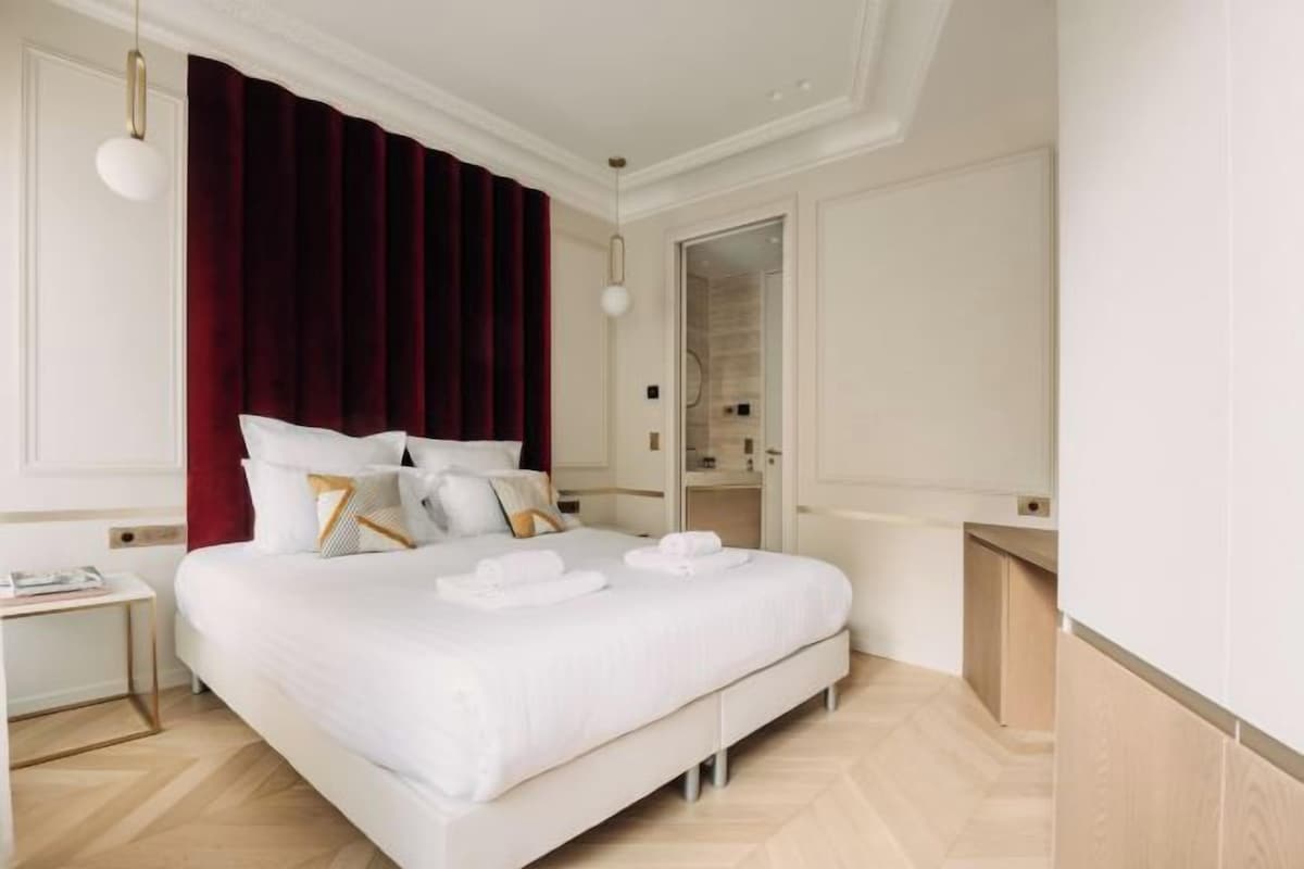 Una habitación de hotel con una cama grande, una mesita de noche, un espejo y un armario.