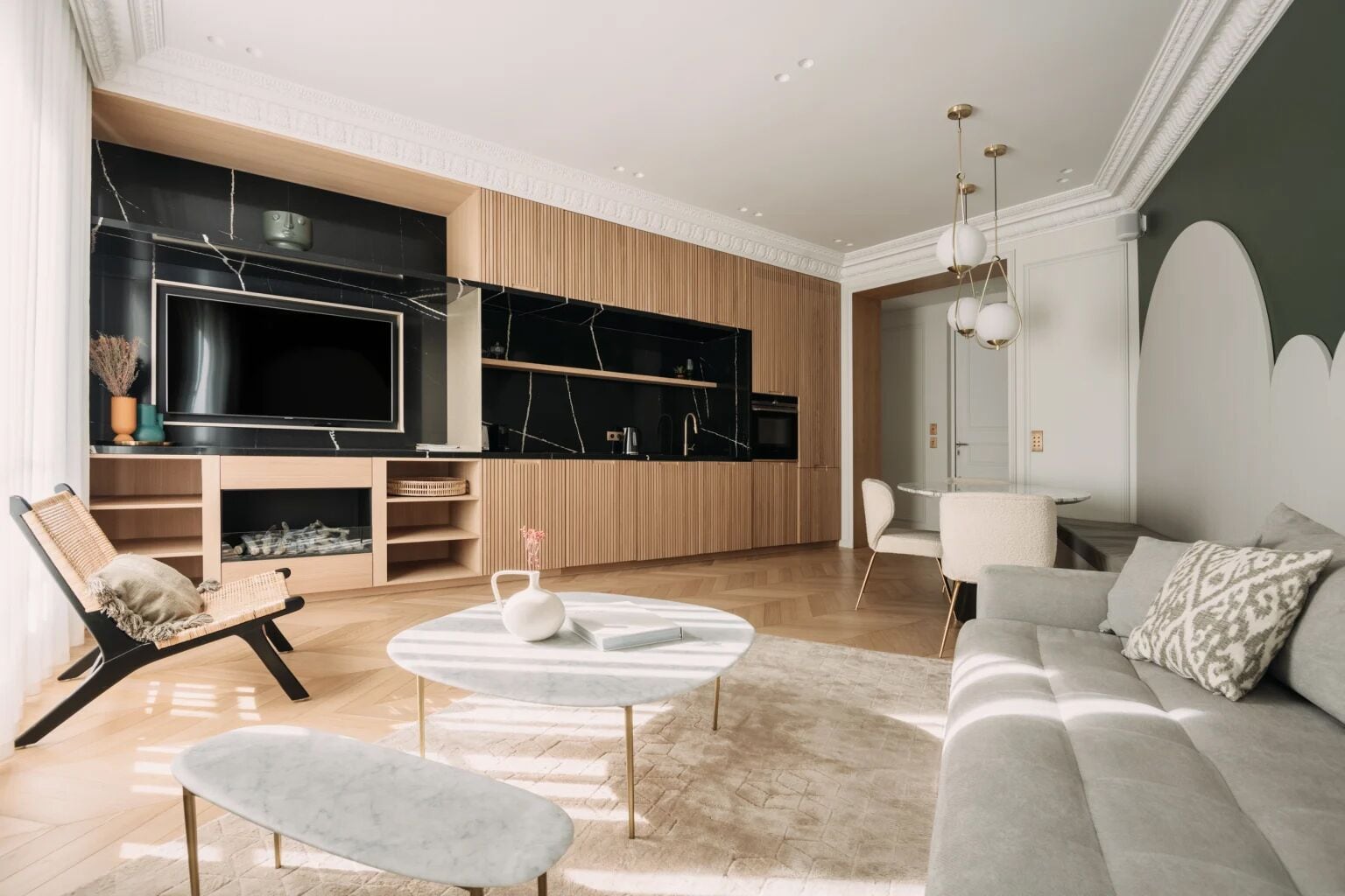 A modern living room with a sofa, a coffee table, a TV, and a kitchen area.