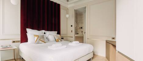A neatly arranged hotel room with a large bed, a bedside table, a mirror, and a wardrobe.