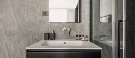 A modern bathroom with a white sink, dark cabinet, and a large mirror.
