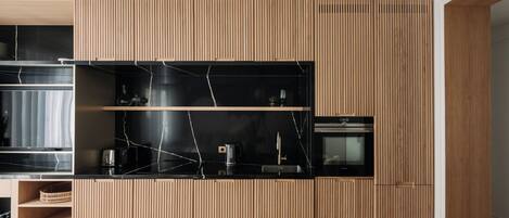 Eine moderne Küche mit Holzschränken, schwarzen Marmorarbeitsplatten und integrierten Geräten.