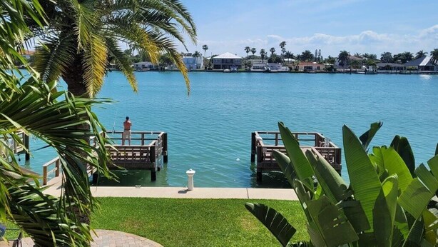 A waterfront property with a dock, palm trees, and a clear view of the water. - Beautiful waterfront condo on intercoastal in Treasure Island (Treasure Island)