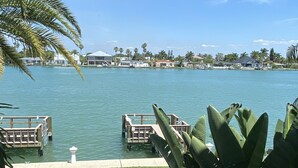 A waterfront view with a dock, palm trees, and a grassy area with a bench. - Beautiful waterfront condo on intercoastal in Treasure Island (Treasure Island)