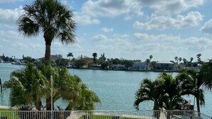 A swimming pool with a view of a lake and palm trees. - Beautiful waterfront condo on intercoastal in Treasure Island (Treasure Island)