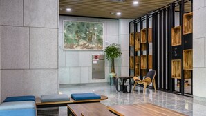 Un hall d’entrée moderne doté d’espaces de détente, d’un comptoir d’accueil et d’une grande œuvre d’art au mur.