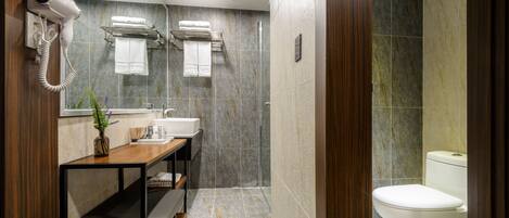 Un baño moderno con secador de pelo, toallero, lavamanos, banco y retrete.