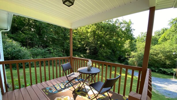 A wooden deck with a railing, a table with chairs, and a patterned rug. - Serenity and Seclusion in Roan Mountain, TN  (Roan Mountain)