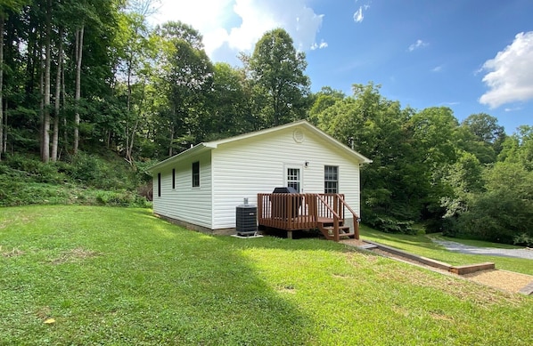 A single-story white house with a wooden deck and a small attached garage.