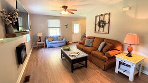 A living room with a ceiling fan, a blue sofa, an orange sofa, a coffee table, and a lamp. - Serenity and Seclusion in Roan Mountain, TN  (Roan Mountain)