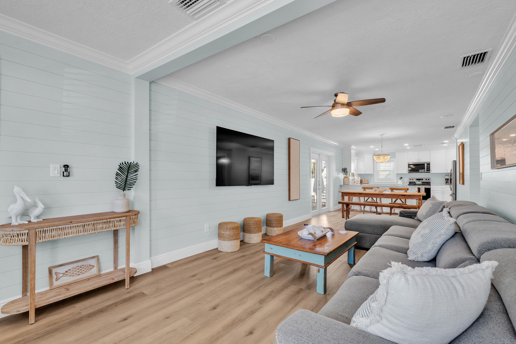 A spacious living room with a wooden console table, a sofa, and a dining area with a table and chairs.