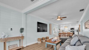 A spacious living room with a wooden console table, a sofa, and a dining area with a table and chairs.