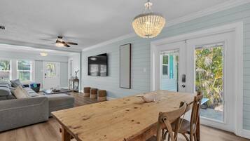 A spacious living room with a wooden dining table, a gray sofa, and a ceiling fan.