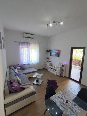 A modern living room with a sofa, a coffee table, a TV, and a dining area with a table and chairs. - Apartment Emily, 4+1 (Sveti Juraj)