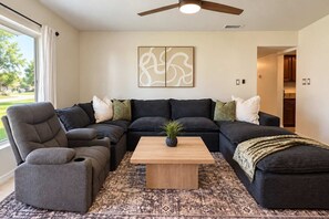 A living room with a sectional sofa, a coffee table, and a ceiling fan. - Family Retreat | Pool, Fire Pit, Ping Pong, Games (Pinellas Park)
