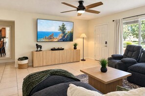A living room with a TV, sofa, coffee table, and a ceiling fan.