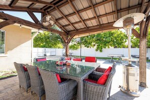 Eine Terrassengruppe im Freien mit einem Tisch aus Glas, Korbstühlen und einem Kaminofen.
