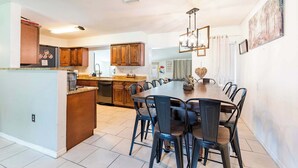 Una cocina moderna con una isla central, armarios de madera y una zona de comedor con una mesa grande y sillas.