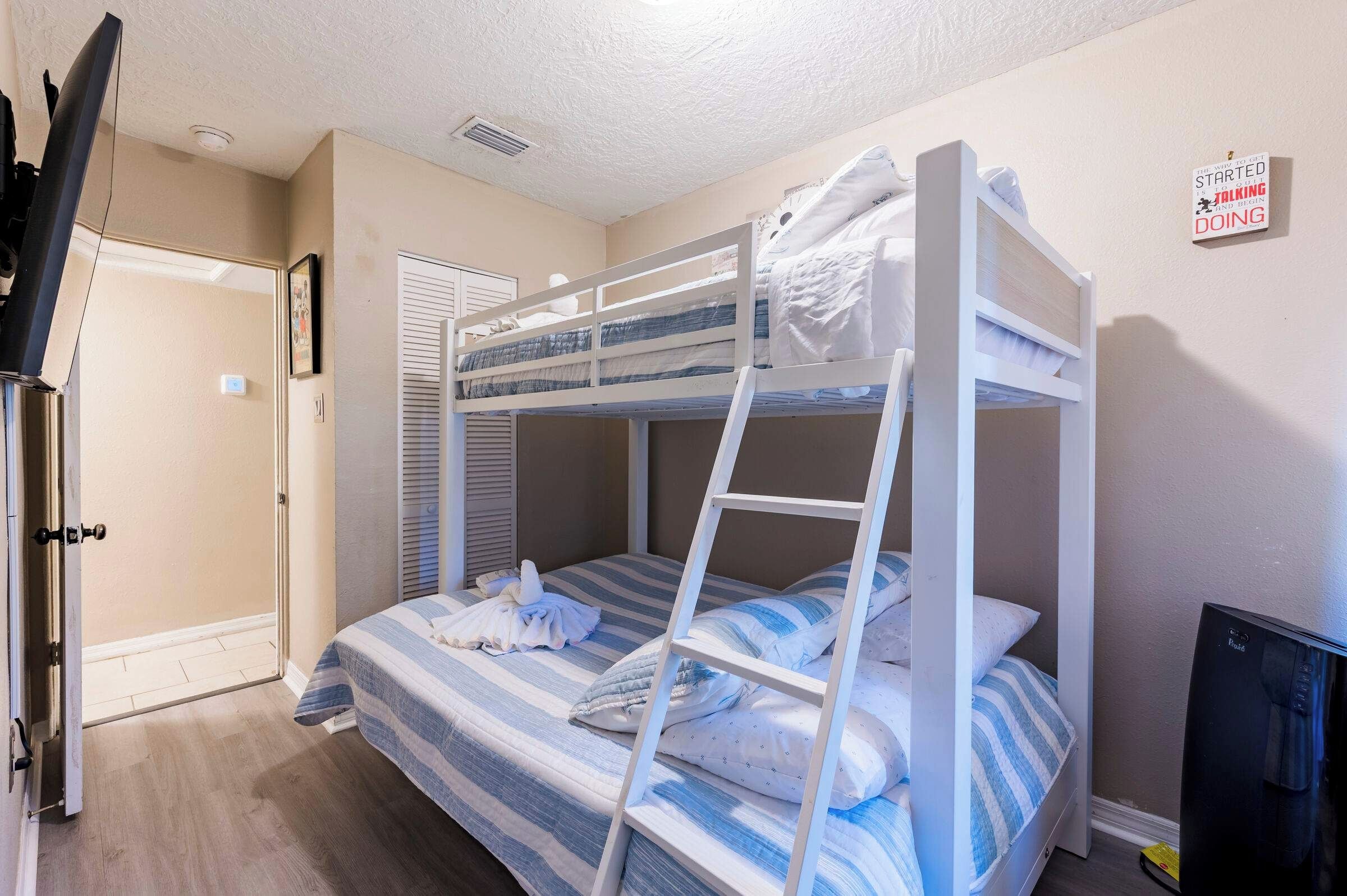 A bunk bed room with a TV, a door, and a sign on the wall.