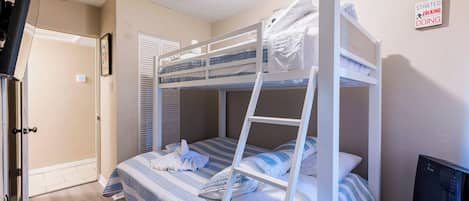 A bunk bed room with a TV, a door, and a sign on the wall.