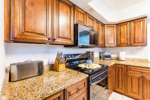 Una cocina con armarios de madera, un microondas de acero inoxidable, un tostador y una estufa.
