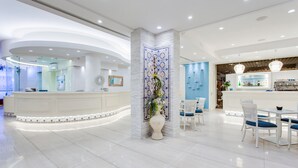 Un moderno vestíbulo de hotel con recepción central, zona de estar y un bar.