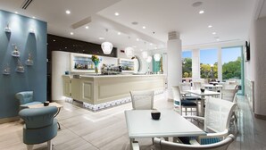 Un moderno vestíbulo de hotel con una zona de bar central, arreglos de asientos y ventanas amplias que ofrecen vistas al exterior.