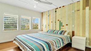 A bedroom with a bed, a nightstand, and a wall with vertical wooden panels.