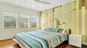 A bedroom with a bed, a nightstand, and a wall with vertical wooden panels.
