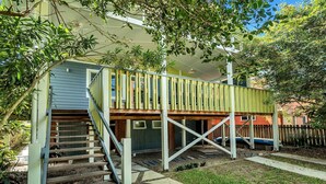 A two-story house with a wooden deck and a staircase leading to the upper level.