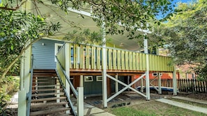 A two-story house with a wooden deck and a staircase leading to the upper level.