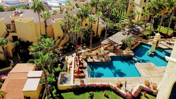 Un complexe hôtelier doté d’une piscine, de palmiers et offrant une vue sur l’océan.