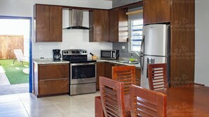 Een kleine keuken met houten kastjes, een roestvrijstalen koelkast, een magnetron, een oven en een gasfornuis.