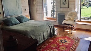 A bedroom with a bed, a chair, a large window, and a door leading outside. - Au Coeur du Banzeau (Noirmoutier-en-l'Île)