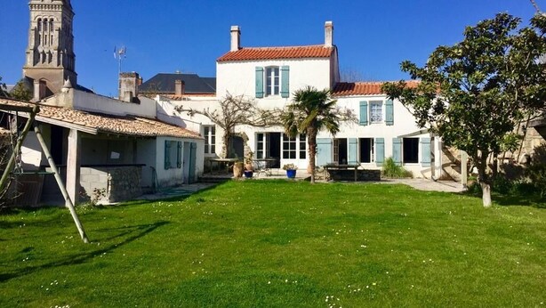 A large house with a tower, a well-maintained lawn, and a clear blue sky. - Au Coeur du Banzeau (Noirmoutier-en-l'Île)